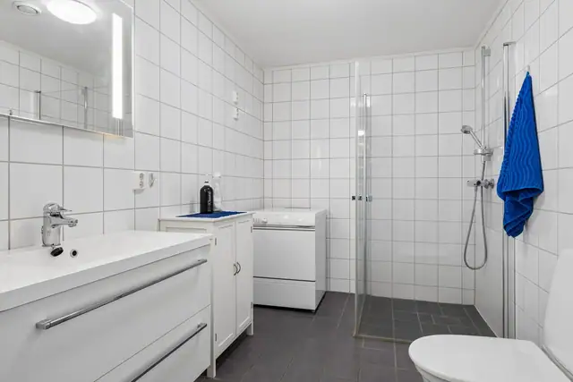 Romslig flislagt bad med varme i gulv. God plass til vaskemaskin og tørketrommel. Dusjvegger i glass.