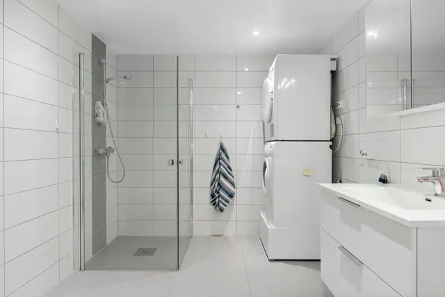Flislagt bed med opplegg for vaskemaskin og tøkretrommel.
