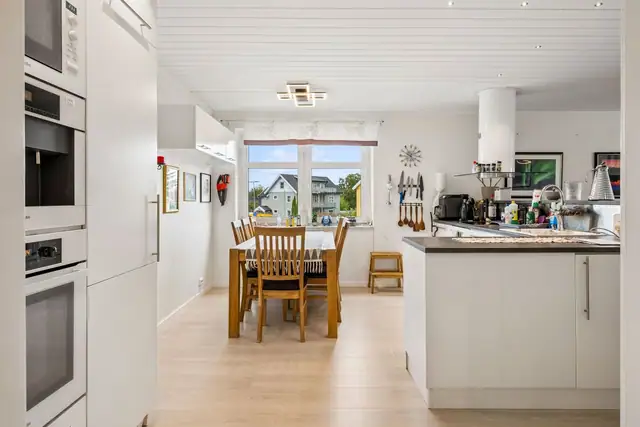 Åpen løsning på kjøkken med nye overskap. Vinduspost med karmer av marmor.