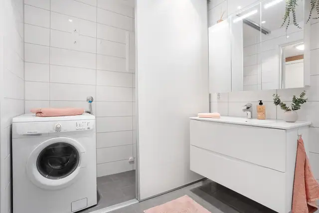 På badet skjules en praktisk vaskeromsløsning bak skyvedør. Opplegg for vaskemaskin og tørketrommel.