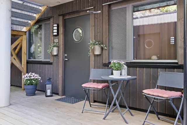 Inngangsparti med plass til sittegruppe mot boder og parkering.