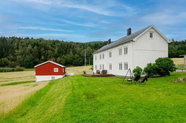 Eiendommen strekker seg mot grønt areal og sjøutsikt i landlige omgivelser