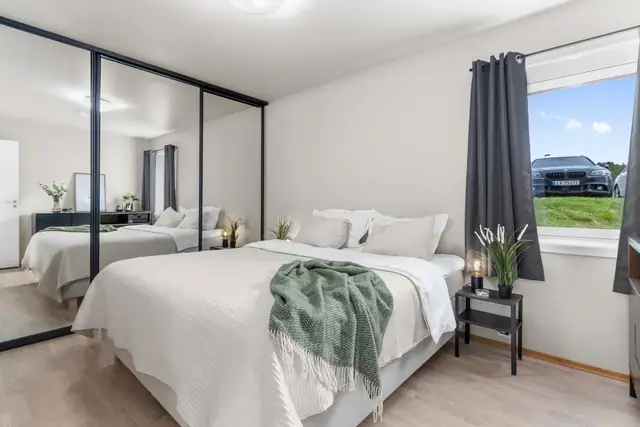 Hovedsoverom med stor skyvedørsgarderobe innredet med Elfa-system.